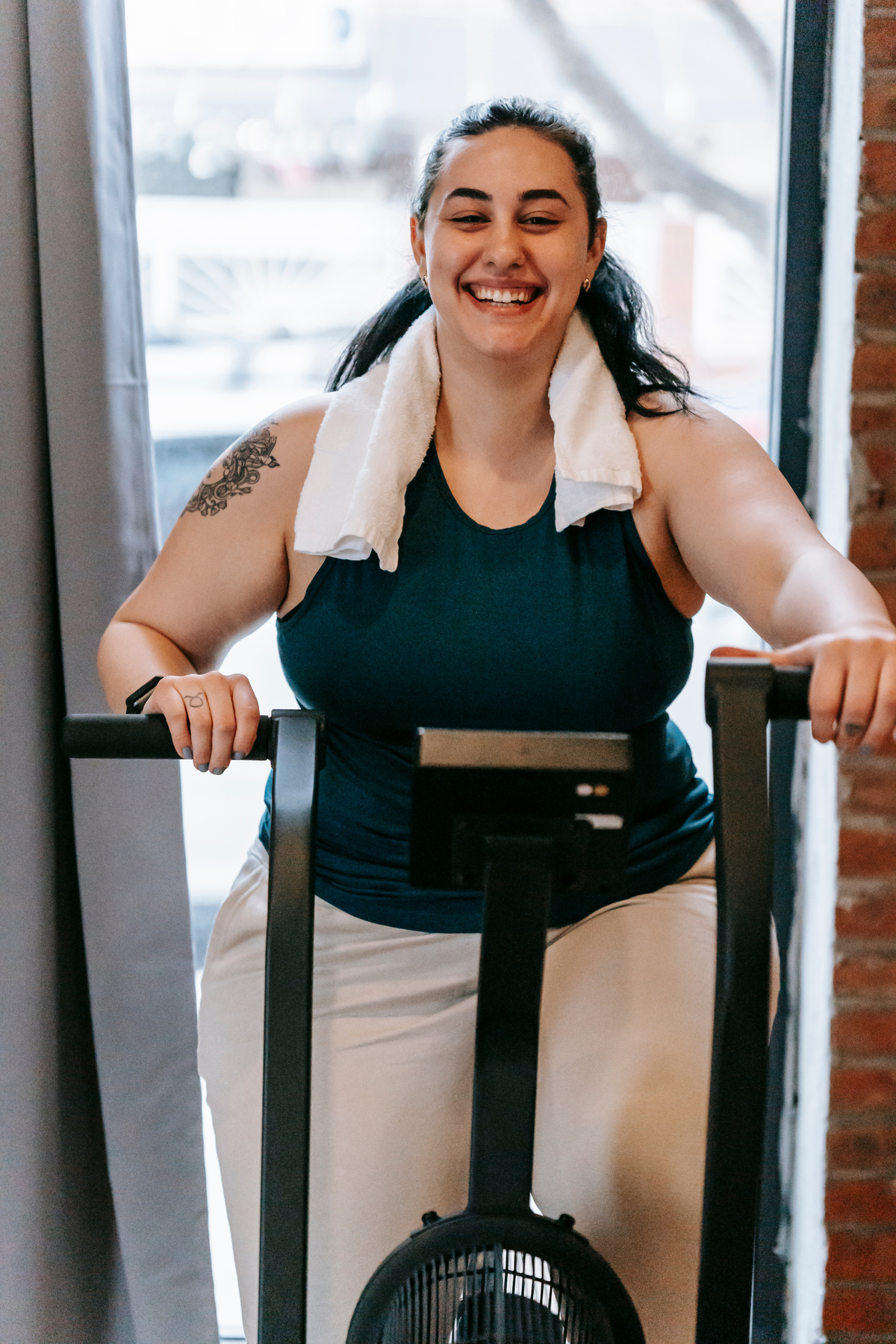 Happy ethnic woman exercising on machine in gym